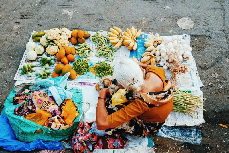Women sitting on ground surrounded by fruits and vegetables
