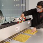 A man operating a machine making mats of straw