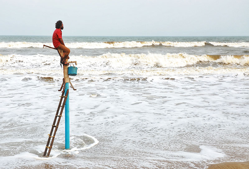 A man on a ladder staring at the sea