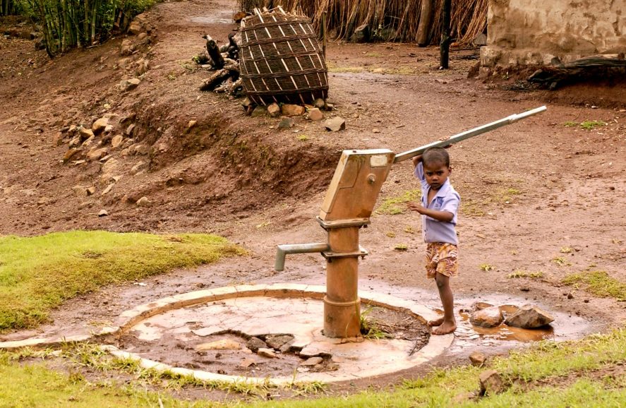 A boy holding onto a water pump