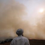 A man watches smoke from a crop fire in India