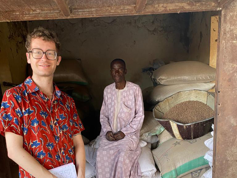 Anthony Wenndt posing with a man sitting on bags of grain