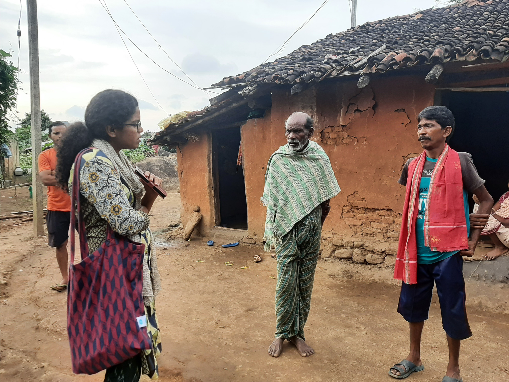 Amrutha Pampackal speaking with two men in a village
