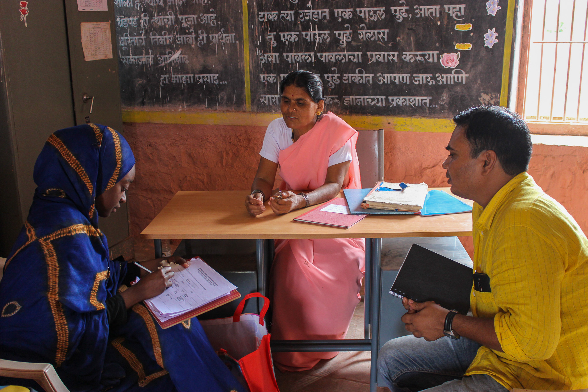 An intern interviews a woman in a school with help from an interpreter