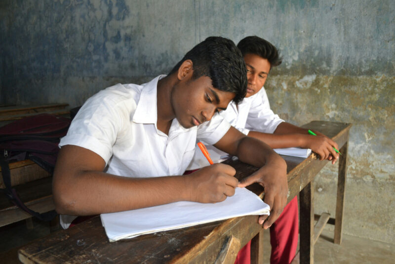 Male students writing in school