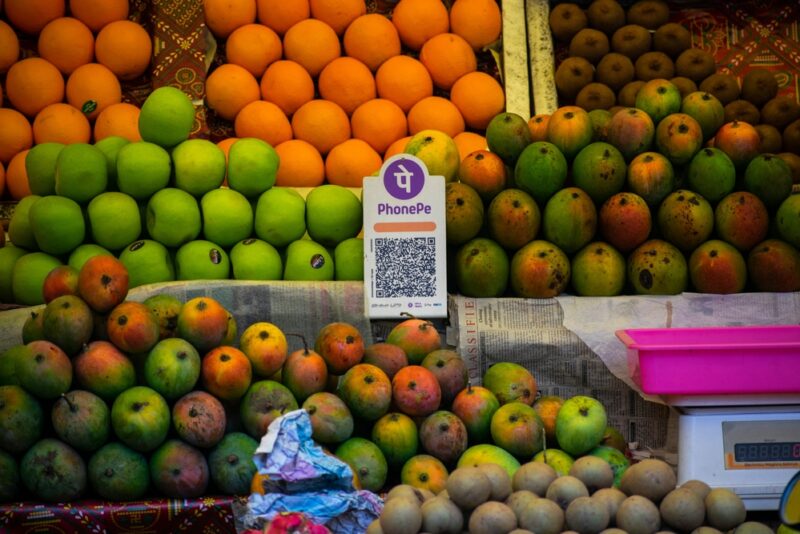A UPI QR code sitting amongst fruit in a market stall