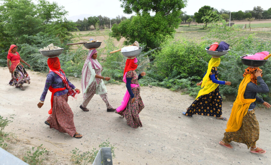 A group of women walking on a road with work supplies