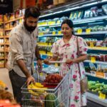 A husband and wife shop in the produce section of a supermarket