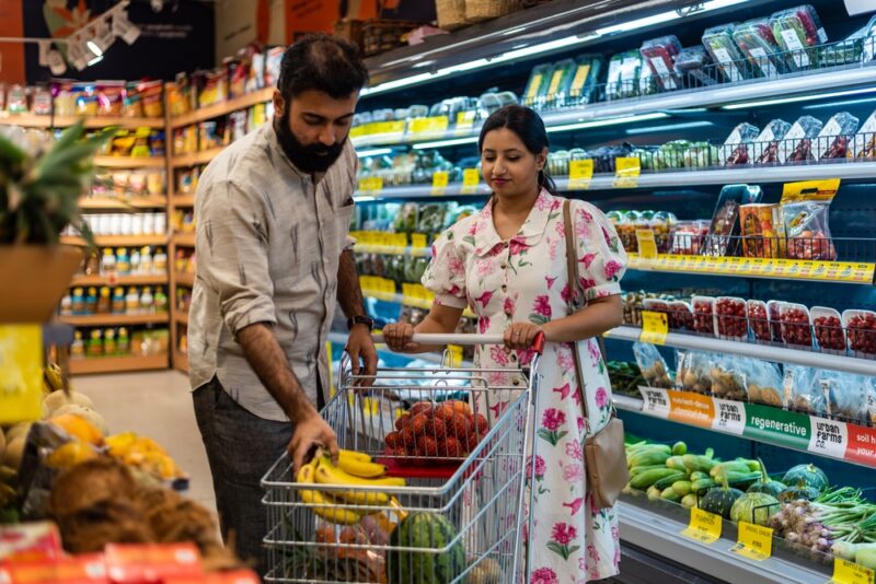 A husband and wife shop in the produce section of a supermarket