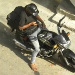 A delivery worker sitting on his motorcycle and looking at his phone