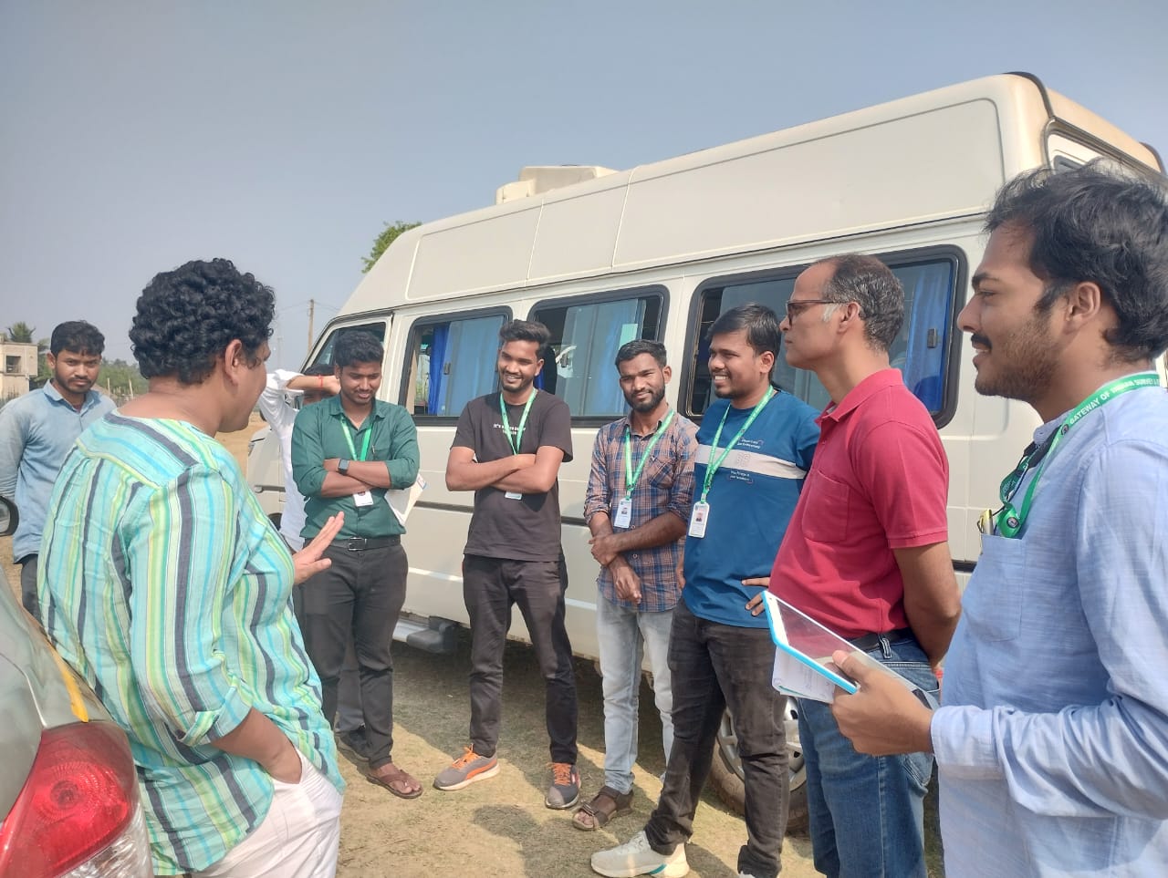 Shree Saha speaks to a group of enumerators in front of a van