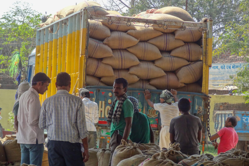 Men standing in front of a truck loaded with bags of pulses