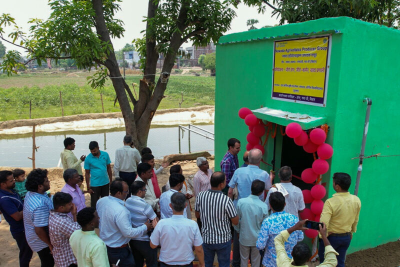 People standing around a green pump house at the inauguration of TCI's agrivoltaics site in Bihar