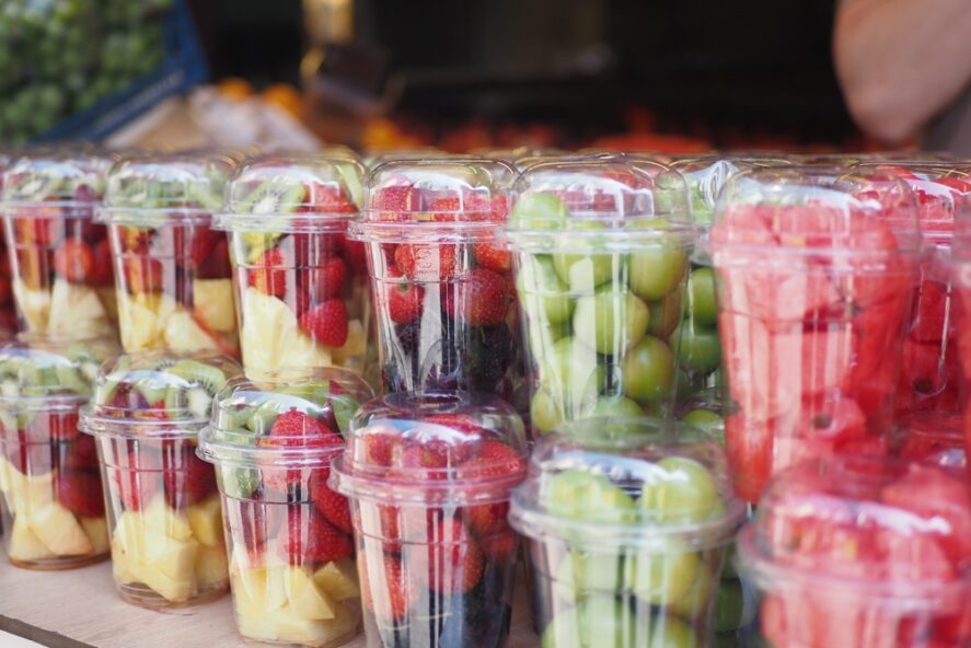 Grapes, strawberries, and cut pineapple stored in round plastic containers