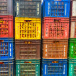 A wall of colorful plastic crates filled with tomatoes