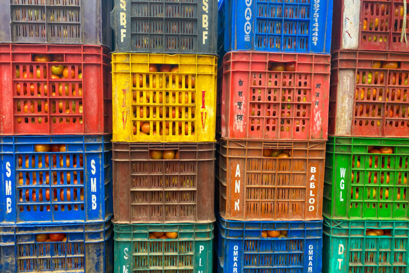 A wall of colorful plastic crates filled with tomatoes