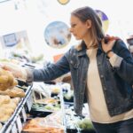 A woman picks up a bag of potatoes at a market