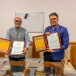 Prabhu Pingali and Chinmay Gotmare posing with signed copies of a memorandum of understanding between TCI and the Ministry of Agriculture