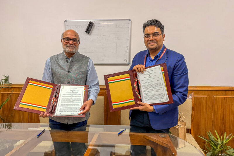 Prabhu Pingali and Chinmay Gotmare posing with signed copies of a memorandum of understanding between TCI and the Ministry of Agriculture