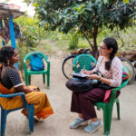 Apurva Borar sitting and interviewing a woman outside