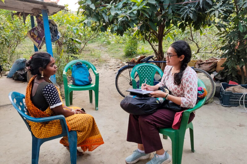 Apurva Borar sitting and interviewing a woman outside