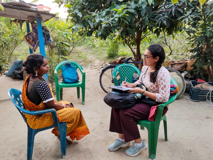Apurva Borar sitting and interviewing a woman outside
