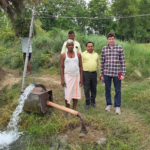 Harrison Sachs and three other men standing by a water pump