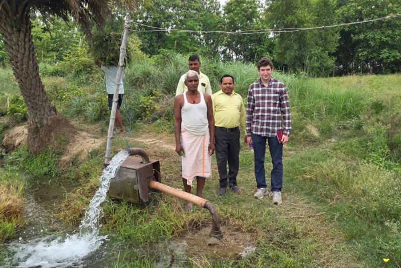 Harrison Sachs and three other men standing by a water pump