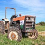 An old tractor painted with the Indian flag parked on farmland
