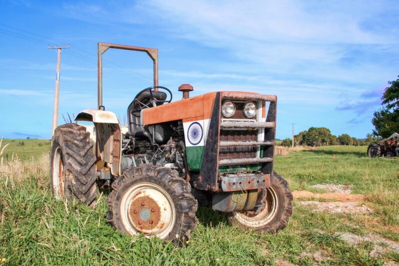 An old tractor painted with the Indian flag parked on farmland